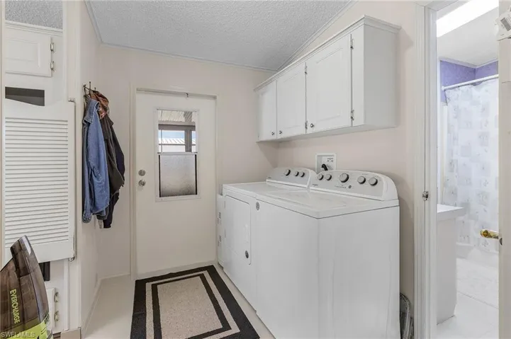 Clothes washing area with cabinet space, a textured ceiling, and washing machine and clothes dryer