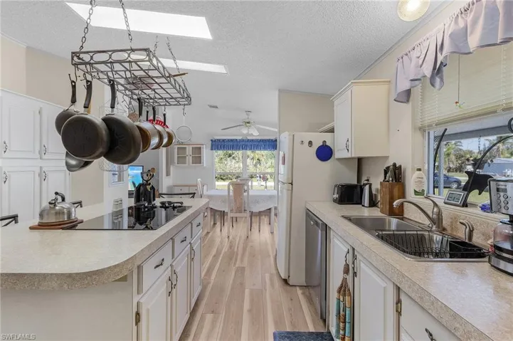 Kitchen featuring light wood-type flooring, a skylight, light countertops, and a sink