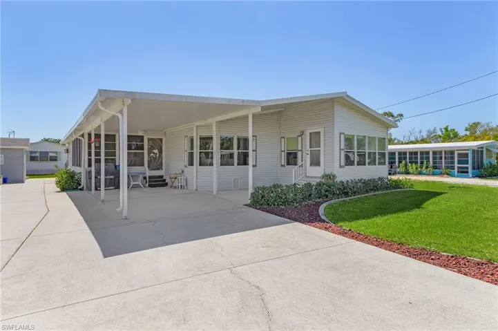 View of front of house featuring entry steps, driveway, a front lawn, and a sunroom