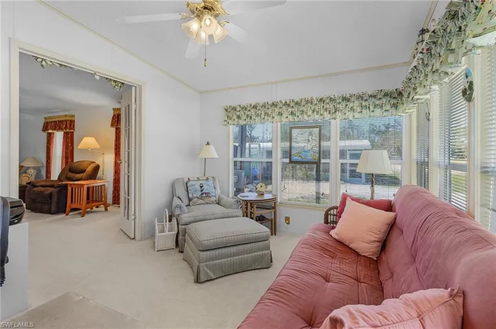 Living room with ceiling fan, carpet floors, ornamental molding, and vaulted ceiling