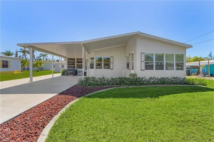 View of front of home with driveway, a carport, and a front yard