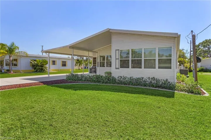 View of front facade with concrete driveway, an attached carport, a front yard, and cooling unit