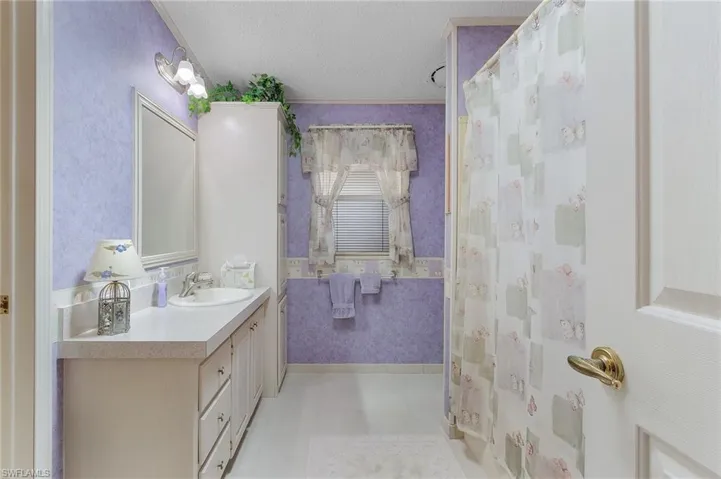 Bathroom with wallpapered walls, a shower with curtain, tile patterned flooring, a textured ceiling, and vanity