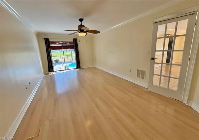 Unfurnished room with light wood finished floors, ornamental molding, and a ceiling fan