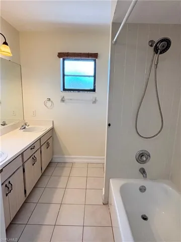 Full bath with double vanity, washtub / shower combination, and light tile patterned floors
