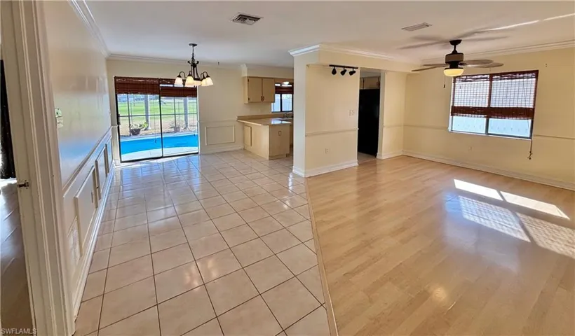 Unfurnished living room with ornamental molding, light tile patterned floors, ceiling fan, and a chandelier
