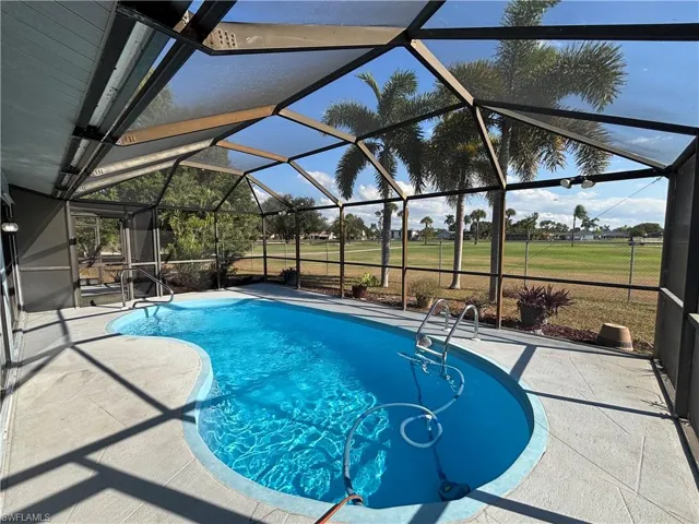 Swimming pool featuring a sunroom, a patio, glass enclosure, and a yard