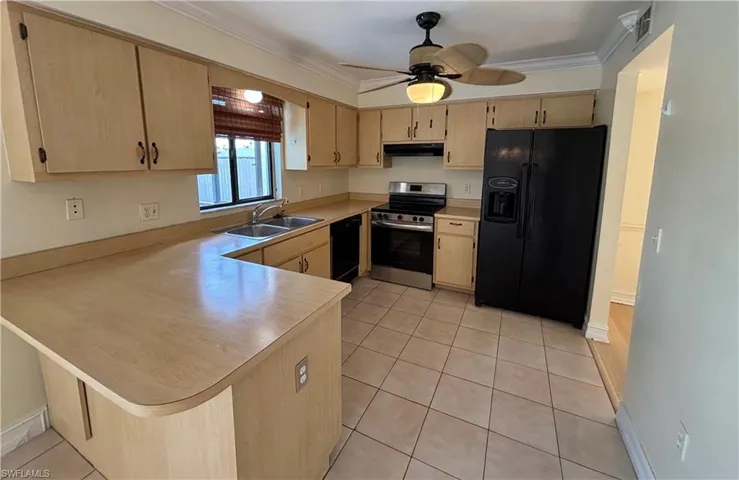 Kitchen with black appliances, light countertops, light brown cabinetry, a peninsula, and light tile patterned floors