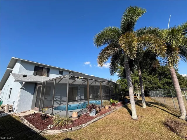 Back of house with stucco siding, a sunroom, glass enclosure, and an outdoor pool