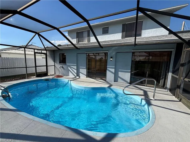 View of swimming pool with a sunroom, glass enclosure, and a patio