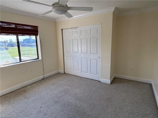 Unfurnished bedroom featuring ornamental molding, ceiling fan, light carpet, and a closet