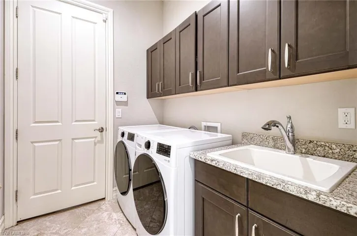 Clothes washing area with washing machine and dryer, sink, and cabinets