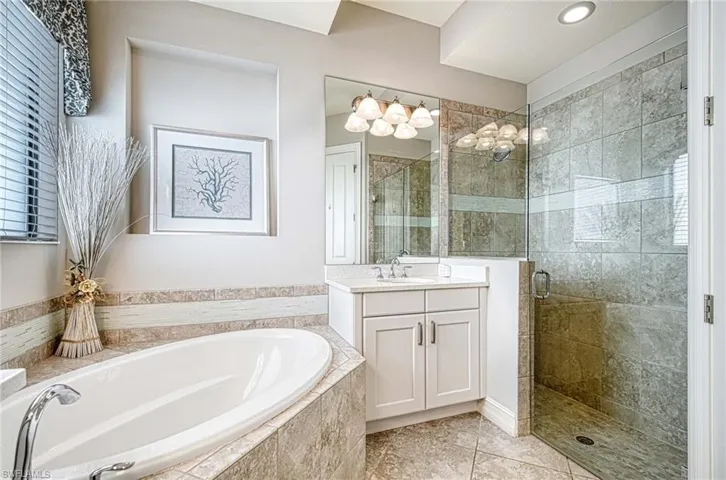 Bathroom featuring tile patterned floors, vanity, and shower with separate bathtub