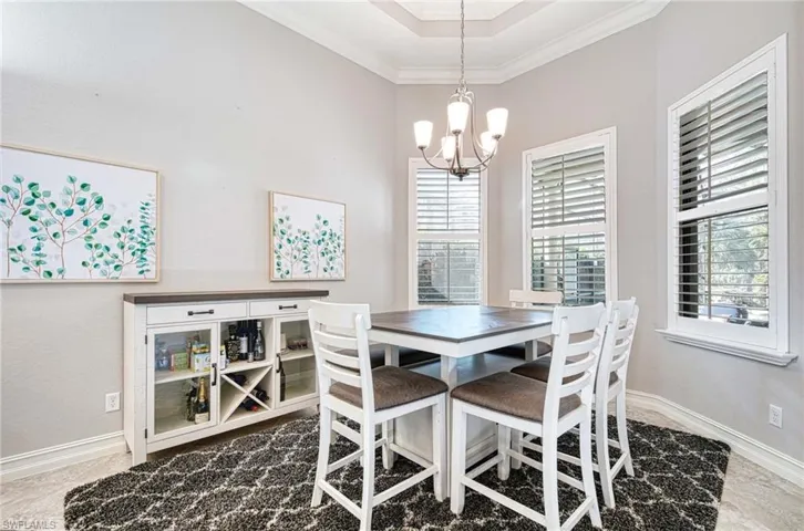 Dining space with an inviting chandelier, a wealth of natural light, and ornamental molding