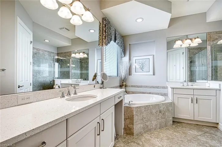 Bathroom featuring a notable chandelier, vanity, and separate shower and tub