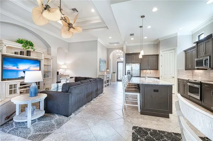 Kitchen featuring backsplash, crown molding, stainless steel appliances, and a kitchen island with sink