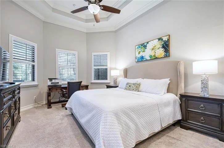 Carpeted bedroom featuring ceiling fan and ornamental molding