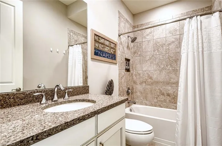 Full bathroom with vanity, shower / bath combination with curtain, and toilet