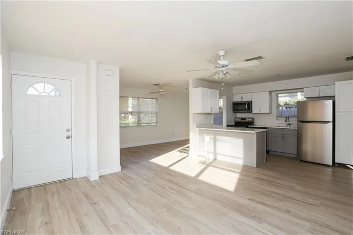 Kitchen with a wealth of natural light, gray cabinetry, light hardwood / wood-style floors, and stainless steel appliances