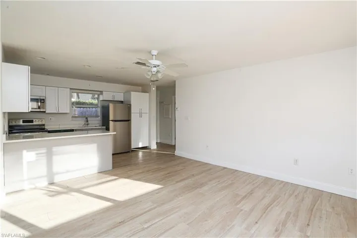 Kitchen with ceiling fan, light hardwood / wood-style flooring, white cabinets, appliances with stainless steel finishes, and sink