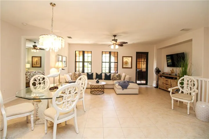Dining area featuring light tile patterned flooring and ceiling fan with notable chandelier