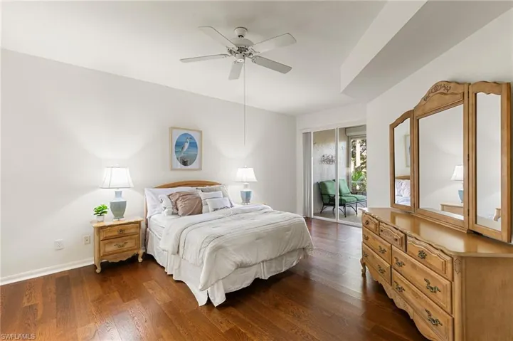 Bedroom with dark wood finished floors, ceiling fan, and access to exterior