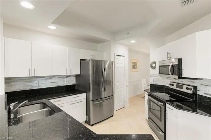 Kitchen featuring stainless steel appliances, white cabinetry, recessed lighting, light tile patterned flooring, and decorative backsplash