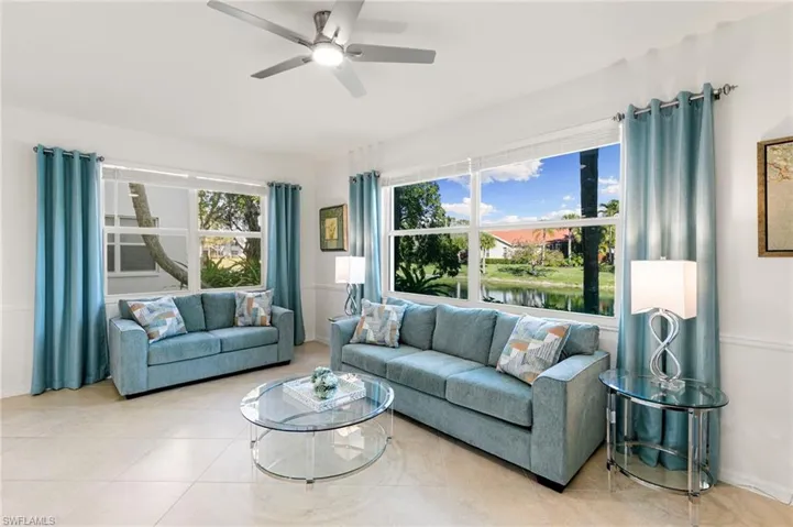 Living area featuring a water view, ceiling fan, and light tile patterned flooring