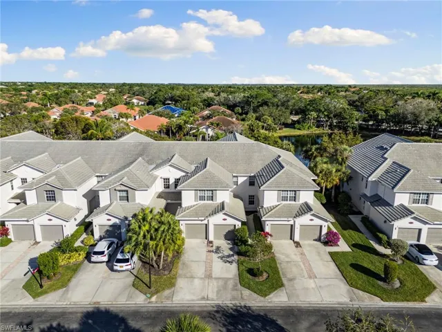 Aerial perspective of suburban area with a nearby body of water and a tree filled landscape