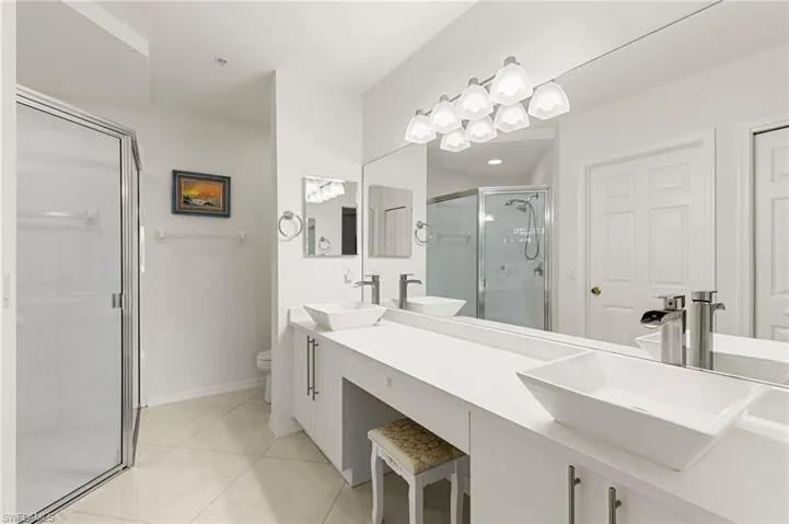 Full bathroom with double vanity, a stall shower, and light tile patterned floors