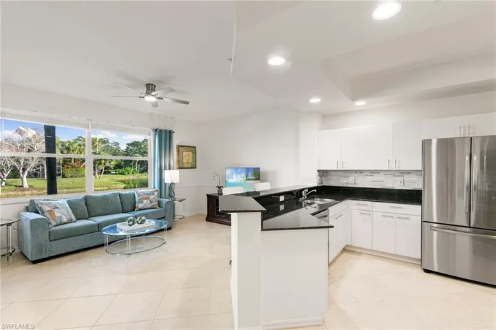 Kitchen featuring freestanding refrigerator, a peninsula, ceiling fan, open floor plan, and white cabinetry