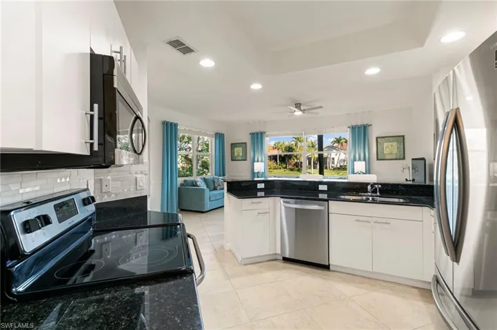Kitchen featuring open floor plan, white cabinetry, stainless steel appliances, ceiling fan, and recessed lighting