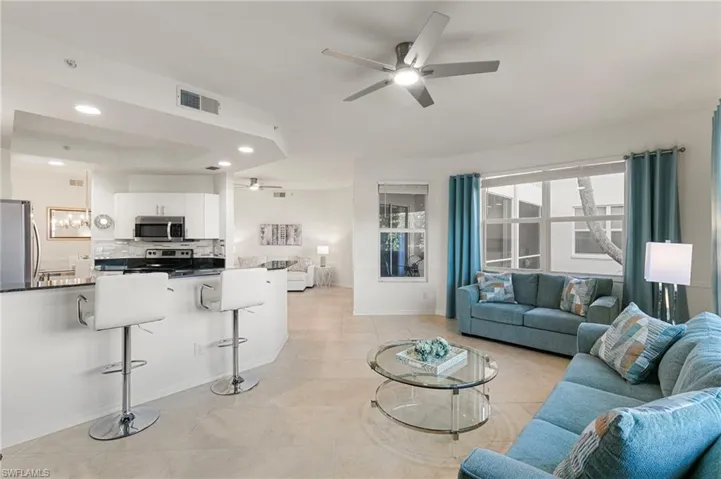 Living area featuring recessed lighting, a ceiling fan, a tray ceiling, and light tile patterned flooring