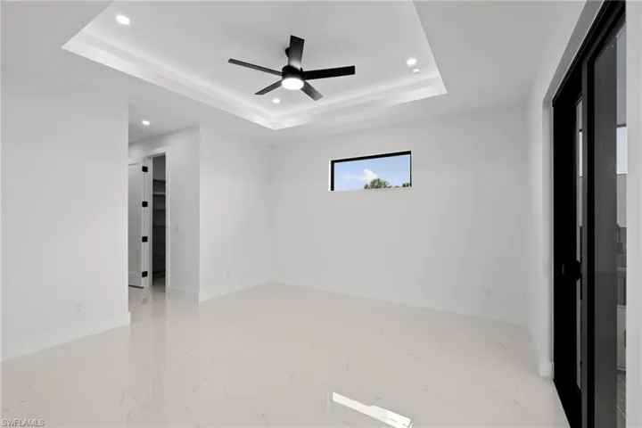 Unfurnished room featuring a raised ceiling, marble finish floors, recessed lighting, and ceiling fan