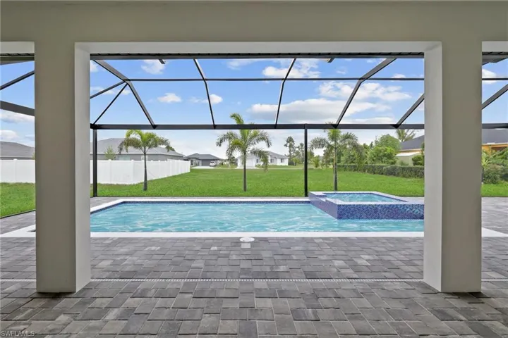 View of pool with a lawn, a patio area, glass enclosure, and a pool with connected hot tub
