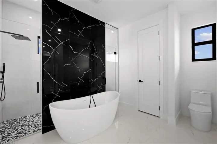 Full bathroom featuring a soaking tub, a marble finish shower, and marble tiled floors