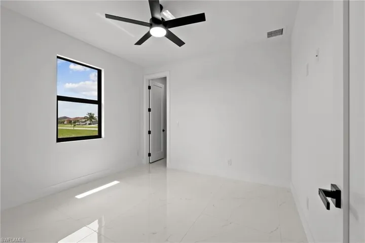 Empty room featuring light marble finish floors and ceiling fan