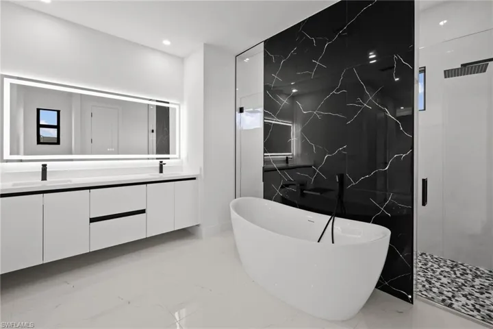 Bathroom with marble tiled floors, double vanity, a freestanding tub, a marble finish shower, and recessed lighting
