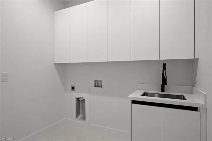 Washroom with cabinet space, marble look tiles, hookup for an electric dryer, and hookup for a washing machine