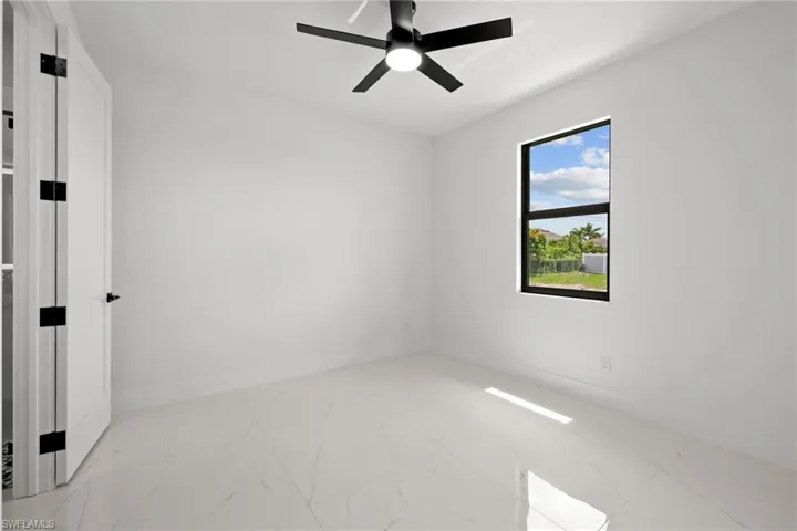 Spare room featuring marble finish floors and a ceiling fan