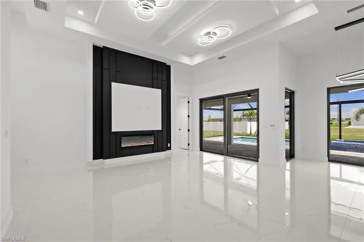 Spare room with a raised ceiling, marble tiled floors, and recessed lighting