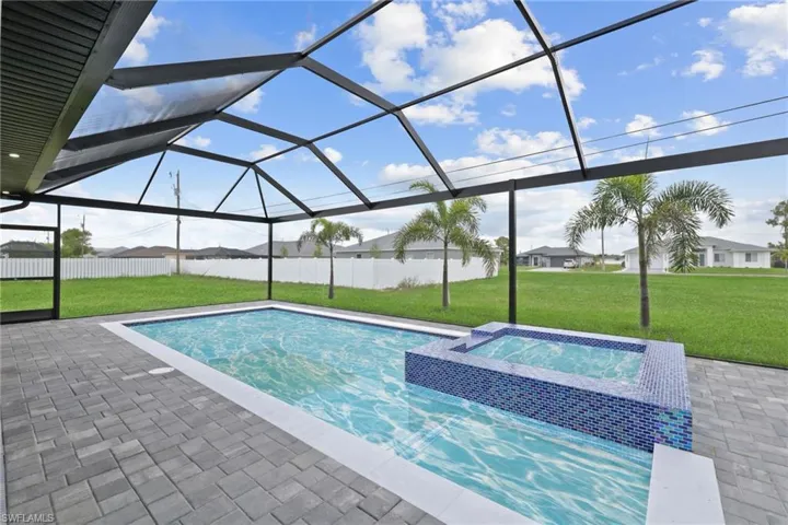 Swimming pool featuring a yard, an in-ground hot tub, a patio, and glass enclosure