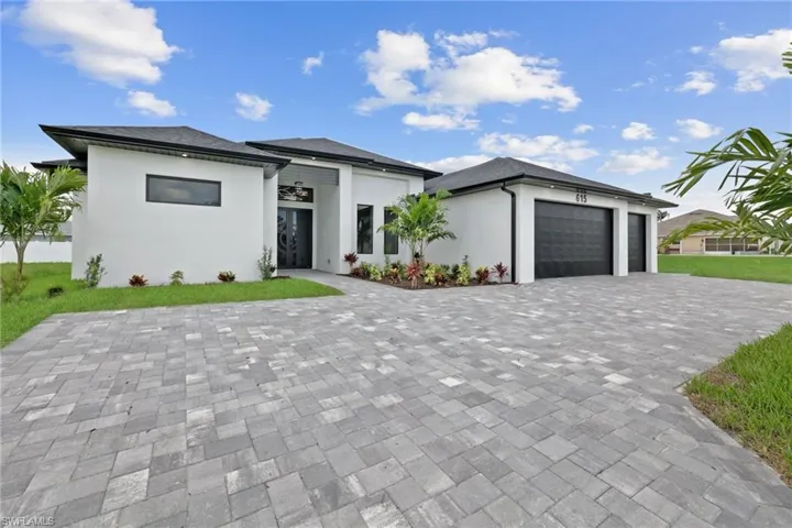 Prairie-style house featuring a garage, stucco siding, and decorative driveway