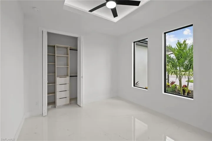 Unfurnished bedroom with marble tiled floors, a ceiling fan, and a closet