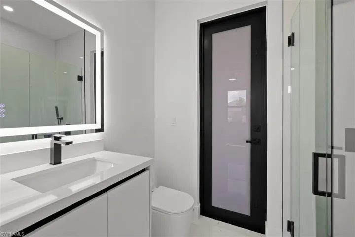 Bathroom featuring vanity, a shower stall, and marble finish flooring