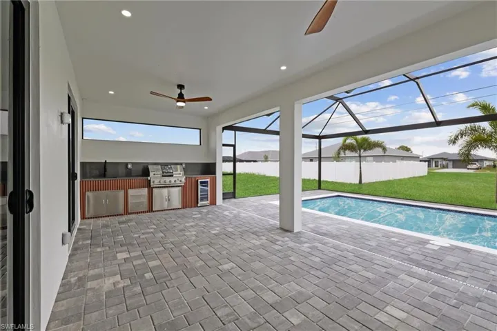 View of swimming pool with ceiling fan, a yard, area for grilling, a patio area, and a water view