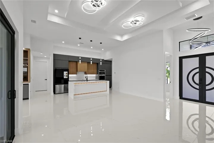 Kitchen with modern cabinets, smart refrigerator, recessed lighting, a tray ceiling, and a center island