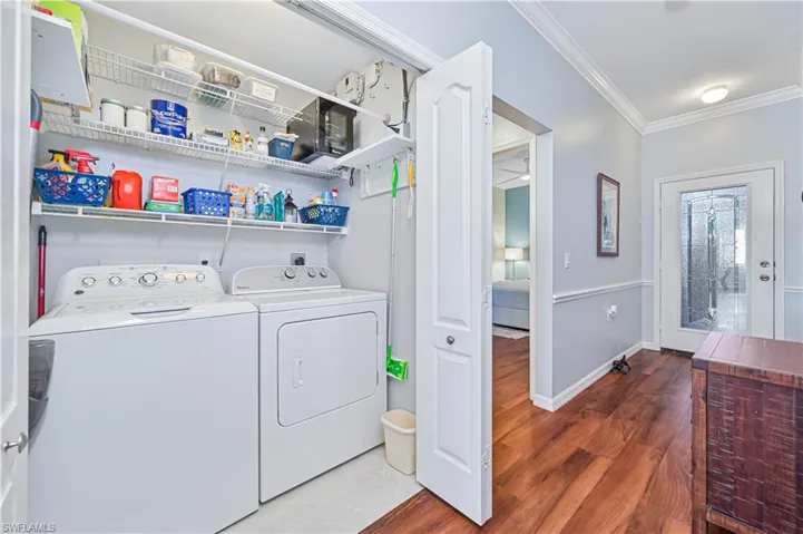 Laundry room with dark hardwood / wood-style flooring, washer and clothes dryer, and crown molding