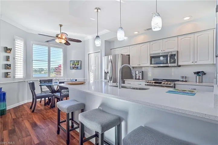 Kitchen with white cabinets, sink, hanging light fixtures, dark hardwood / wood-style flooring, and stainless steel appliances