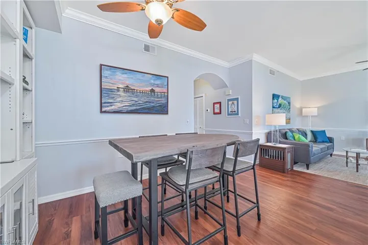 Dining area with dark hardwood / wood-style floors, ceiling fan, and ornamental molding